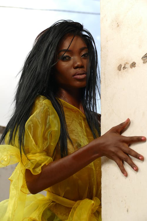 Black woman in yellow transparent blouse looking at camera