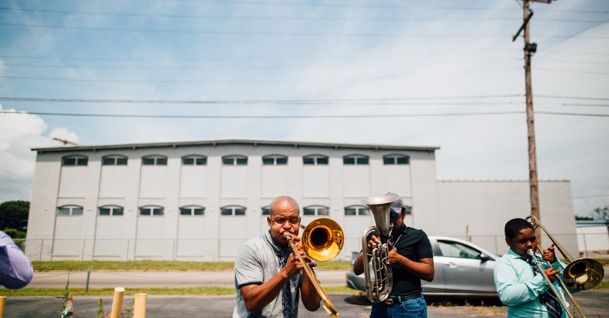 Group of creative African American male musicians playing musical instruments while spending time together on sunny day