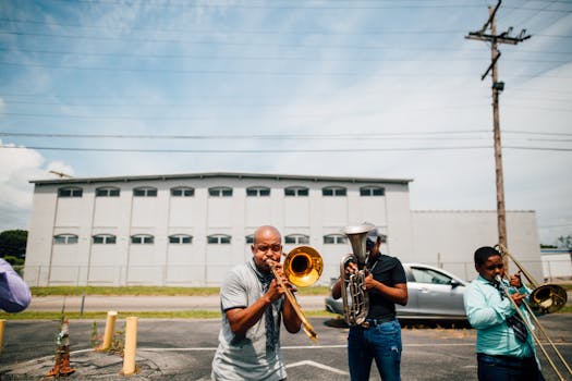Group of creative African American male musicians playing musical instruments while spending time together on sunny day