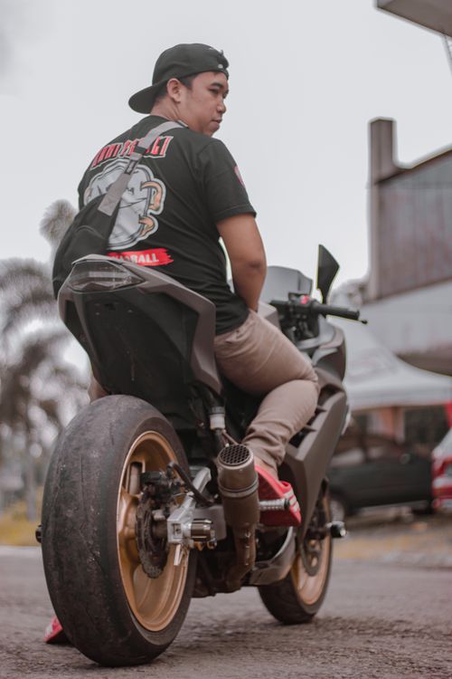 Free Man in casual attire sitting on a motorcycle outdoors, showcasing urban lifestyle. Stock Photo