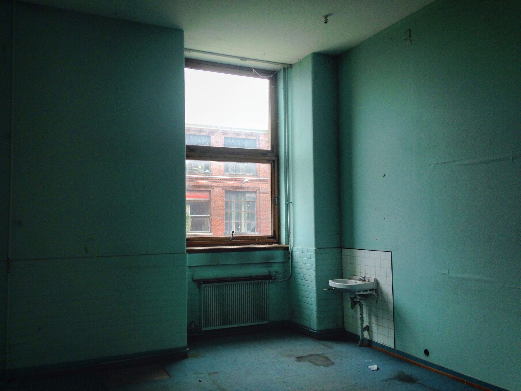 An empty room with a large window and sink, showcasing industrial architecture.. empty, room, with