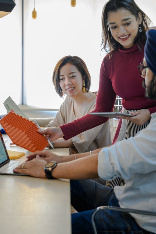 Young Women and Man Talking at Office Desk