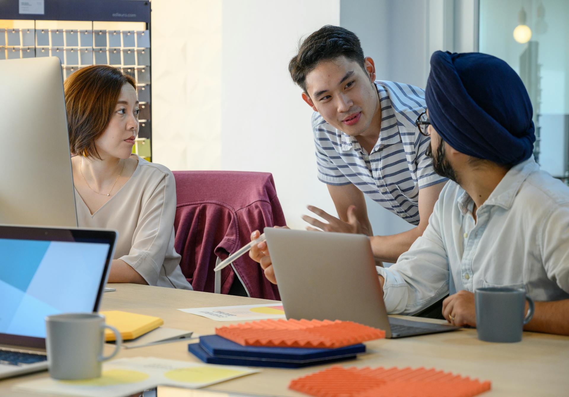 A diverse team engaged in a business meeting discussing ideas with laptops.