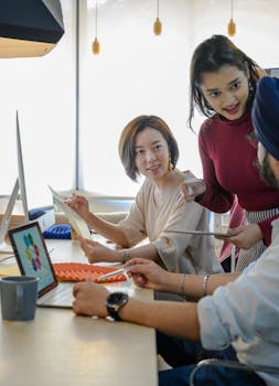 Professional team working together in a modern office space with laptops and discussions.