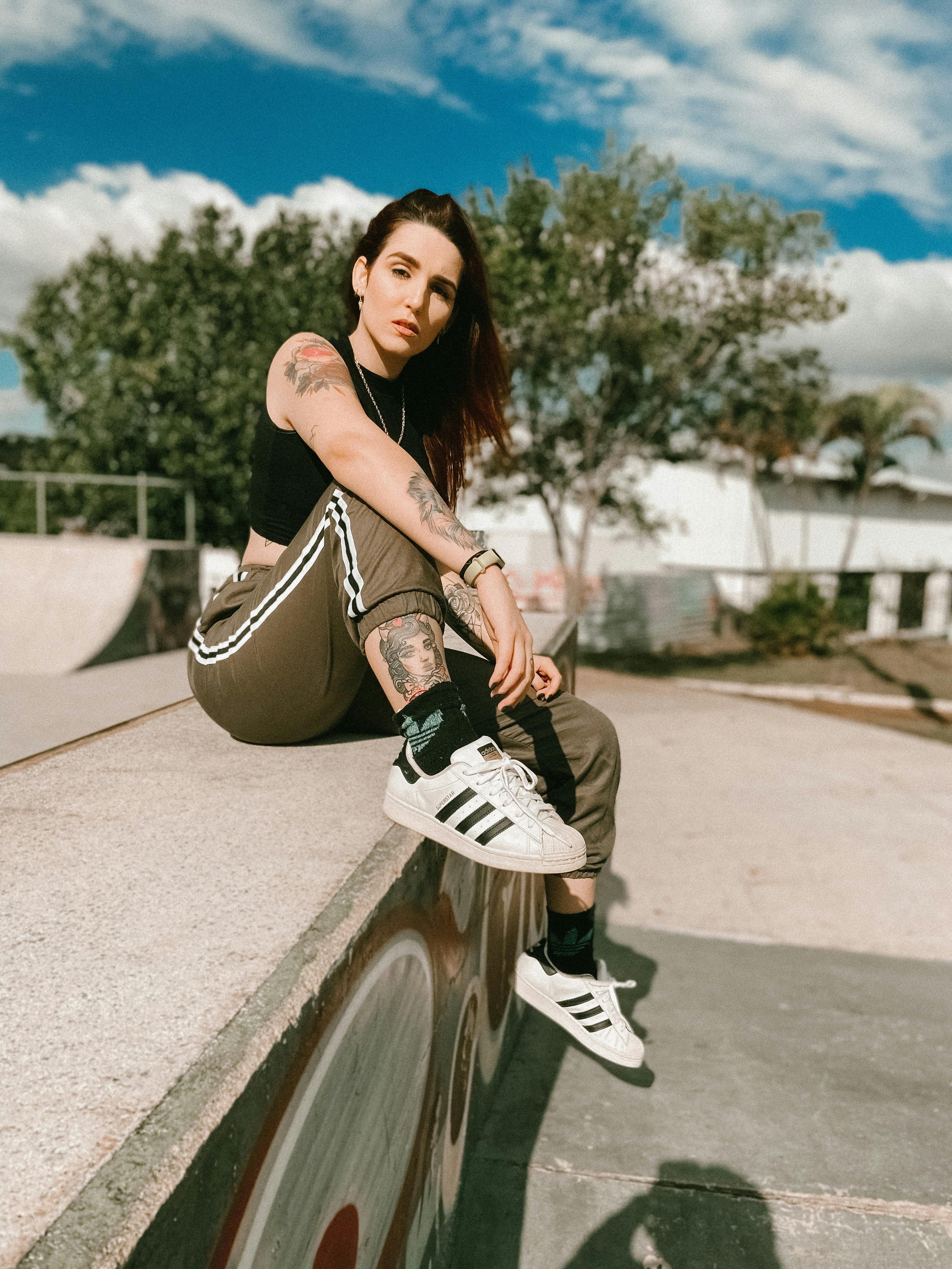 young hipster tattooed woman sitting on skate ground