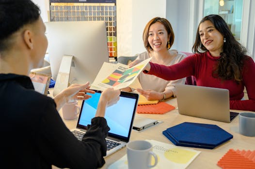 A diverse group of women sharing ideas and documents in a modern office setting.