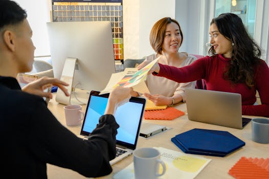 A diverse team collaborating with laptops and documents in a modern office setting.