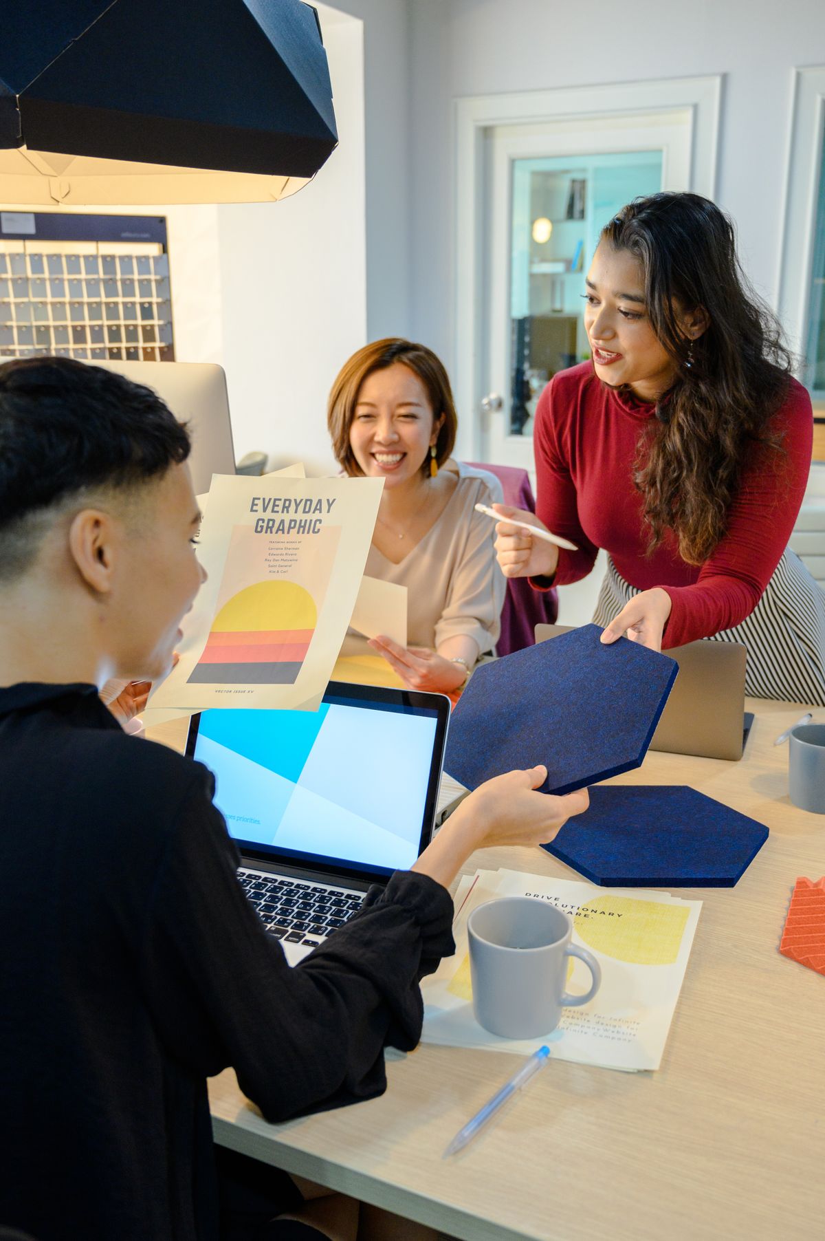 Design team discussing printed graphics and digital work at a table