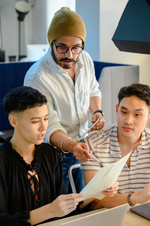 Free Three professionals engaged in a teamwork session, reviewing documents and planning. Stock Photo