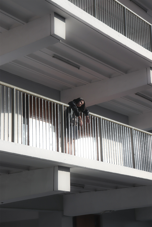 Free A tired young woman leans on a metal railing in a modern building. Stock Photo