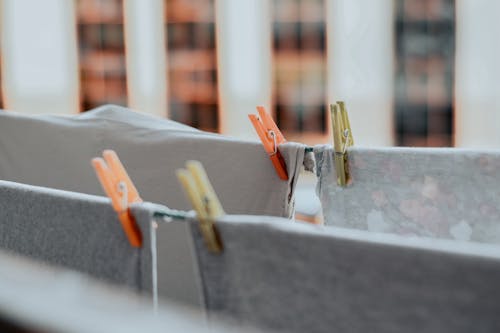 Washed fresh laundry of grey cloth hanging on ropes with colorful clothespins attached