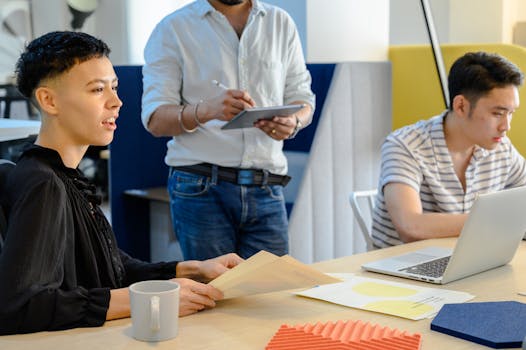 Three diverse coworkers collaborating in a modern office setup with technology.