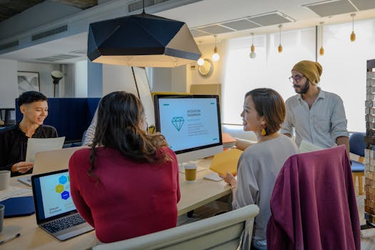 Diverse team engaging in a collaborative office meeting with laptops and presentations.