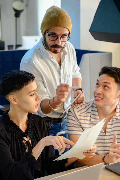 Free Three colleagues engaged in a collaborative discussion at the office, reviewing documents and sharing ideas. Stock Photo