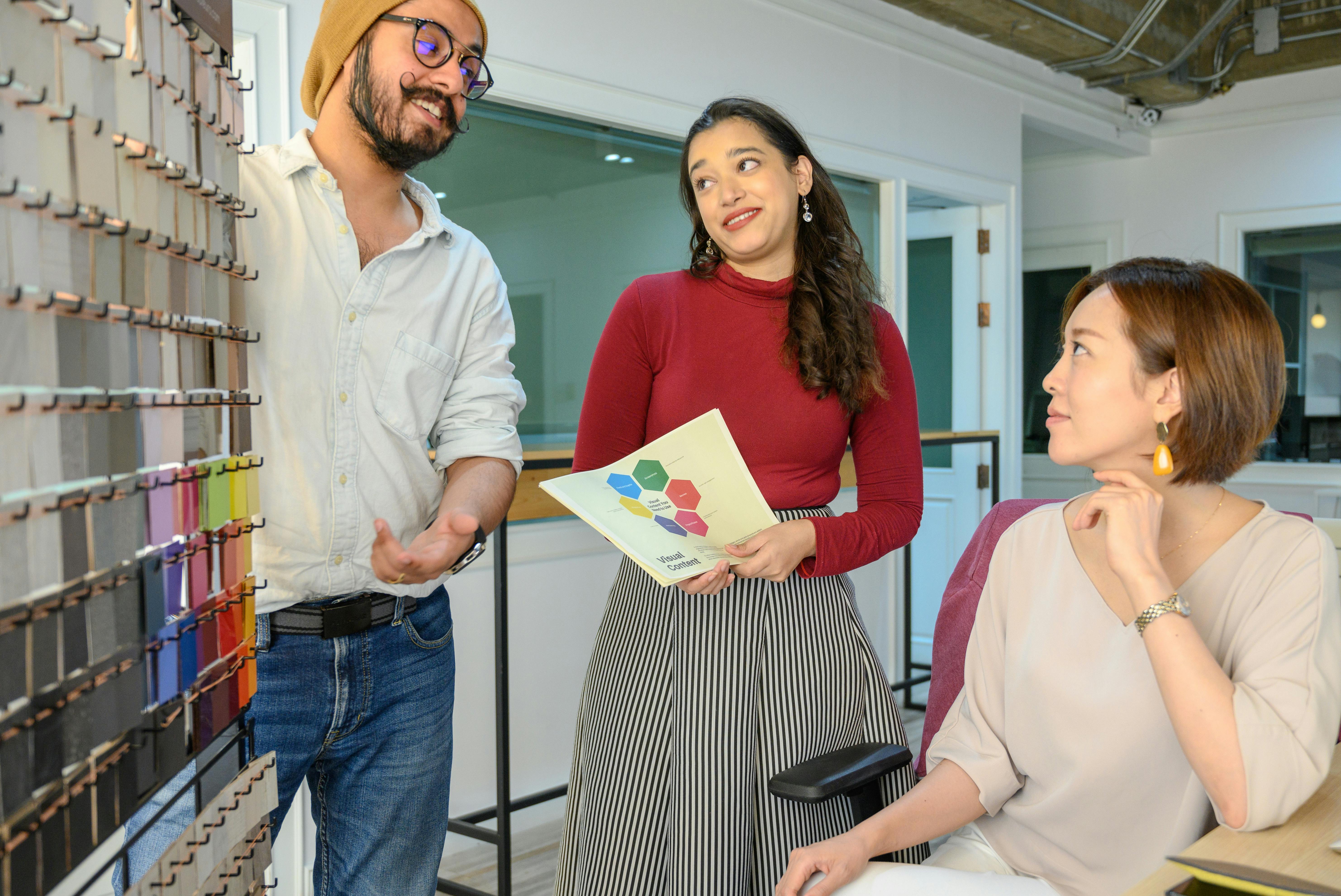 Three colleagues discussing design concepts in a contemporary office setting.