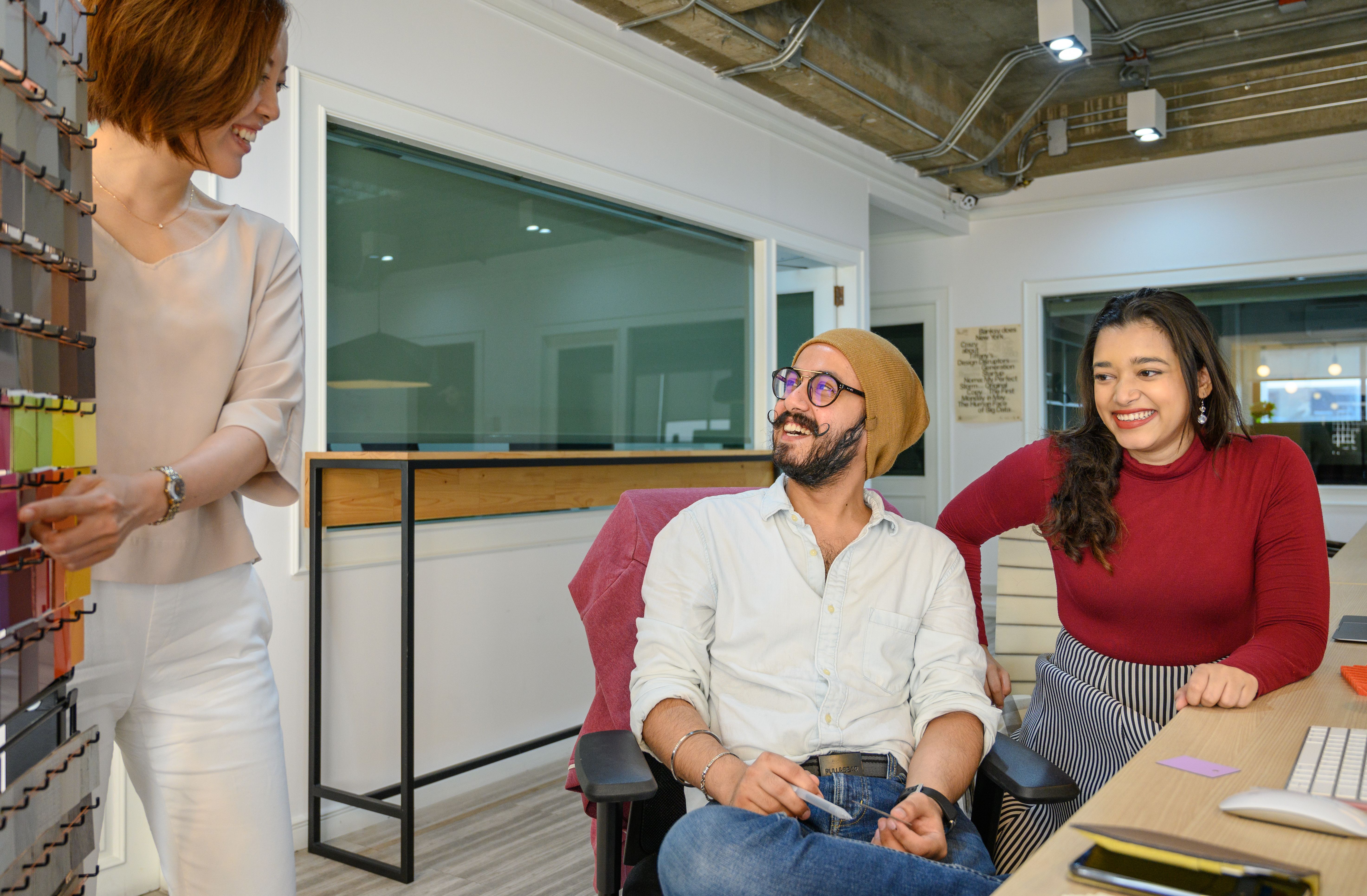 A diverse group of adults smiling and working together in a modern office setting.