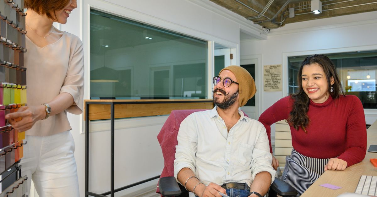 A diverse group of adults smiling and working together in a modern office setting.