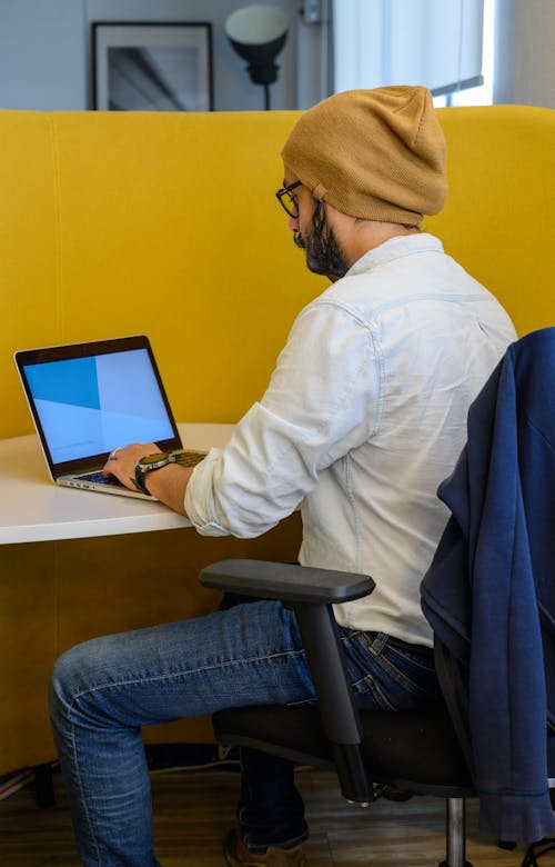 Man Using a Laptop Sitting on a Black Office Chair