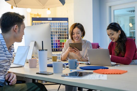 Diverse team members working together on a project with technology and smiles in a modern office setting.