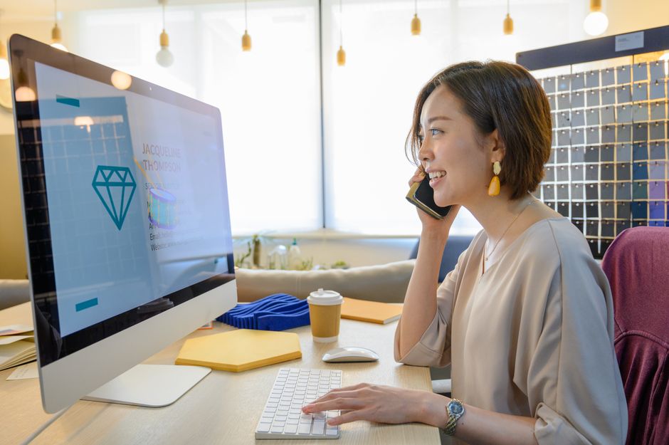 活気あるオフィス環境で電話とコンピュータを使いこなす自信に満ちたビジネスウーマン。