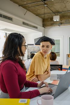 两个人在现代化的办公空间里用笔记本电脑讨论