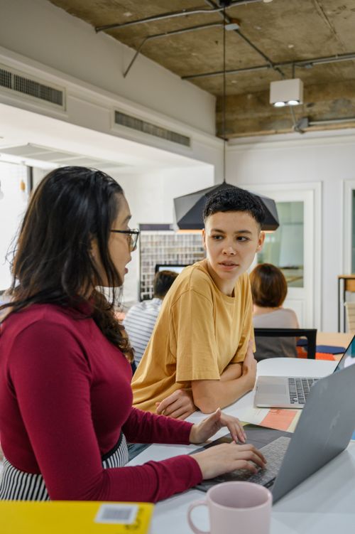 Free Two people engaged in discussion at a modern office workspace with laptops. Stock Photo