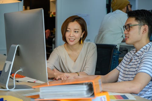 Man and Woman Sitting while Looking at the Computer Monitor 