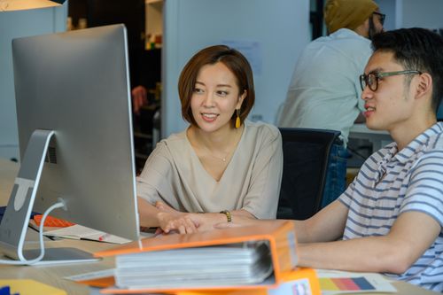 Free Two young adults engaged in a collaborative discussion at a modern workspace. Stock Photo