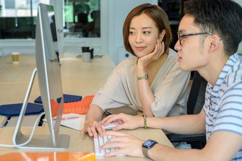 Free Two colleagues collaborating at a computer, discussing a project in a modern office setting. Stock Photo