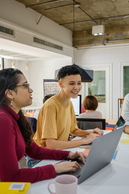 Free Young professionals collaborating in a modern office environment with laptops and coffee. Stock Photo