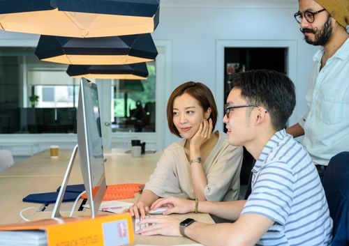 Free Diverse team of office workers collaborating on a computer project, fostering teamwork and innovation. Stock Photo