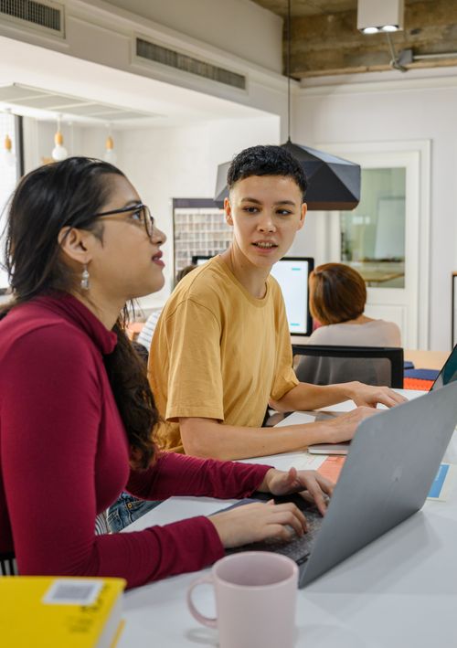 Free Two adults collaborate on laptops in a modern office, fostering a dynamic and innovative environment. Stock Photo