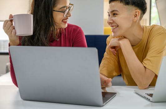 同事们微笑着在室内一起工作，手里拿着笔记本电脑和咖啡