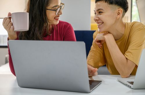 Free Smiling colleagues working together with laptops and coffee indoors. Stock Photo