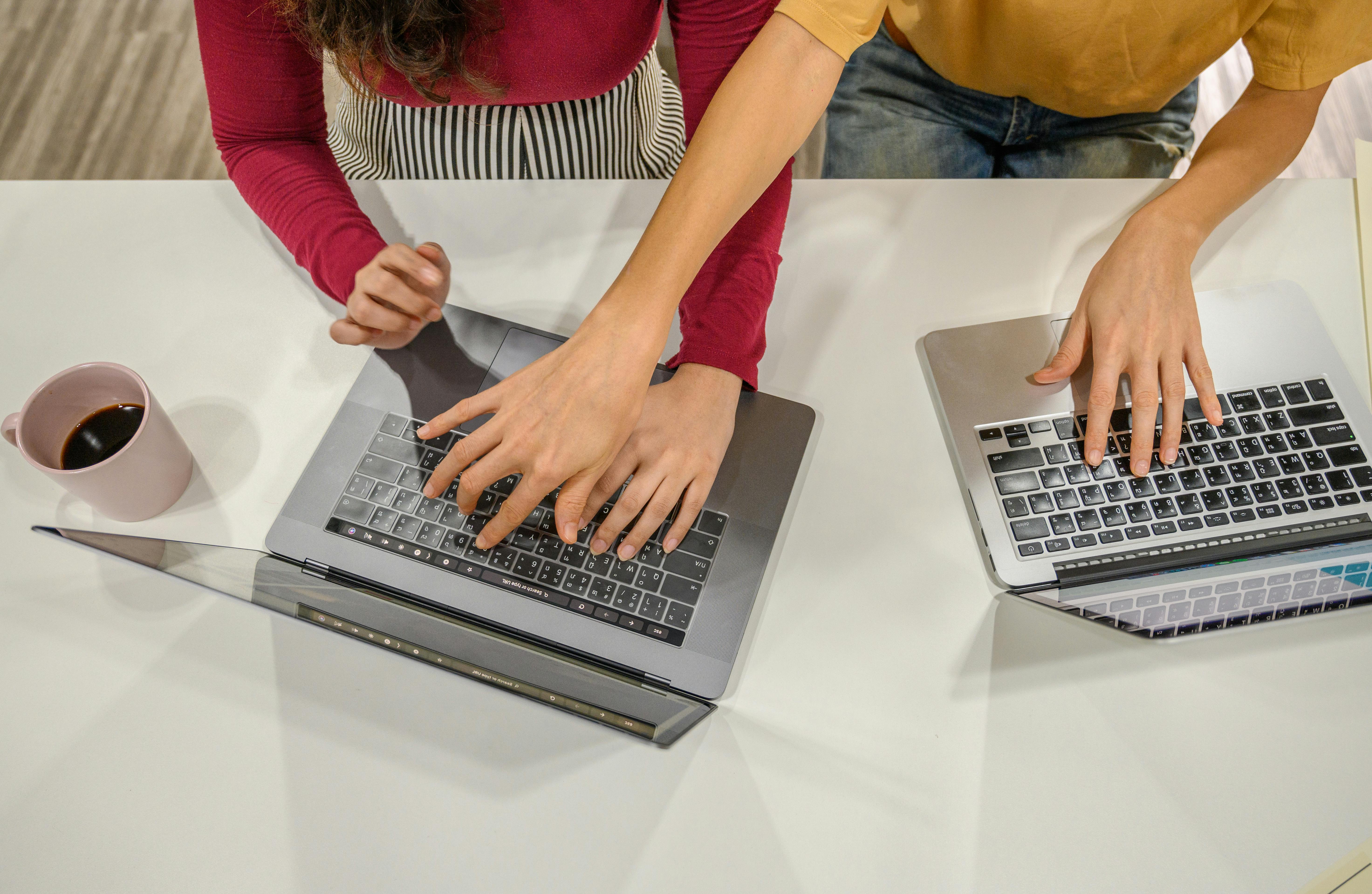 An image of two women typing on laptops