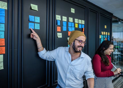 Collaborative brainstorming session with smiling colleagues using sticky notes in a modern office setting.
