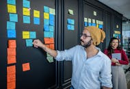 商业专业人士利用办公室墙上的便利贴来促进团队合作