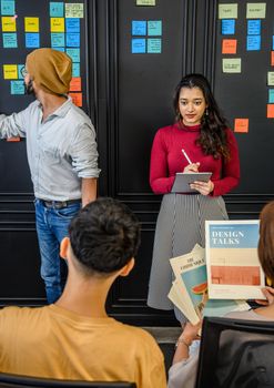 Diverse group in a vibrant office with sticky notes brainstorming and discussing design ideas.