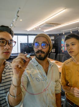 Diverse team collaborating on project ideas written on a clear board in a modern office.