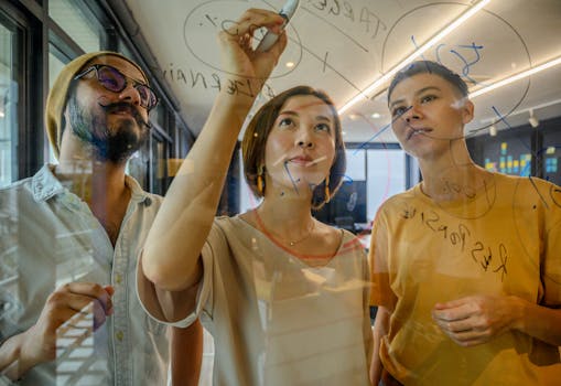 Group of diverse professionals collaborating on a glass board in a modern office setting.