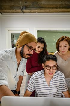 在现代办公空间中，多元化的团队围绕计算机进行合作
