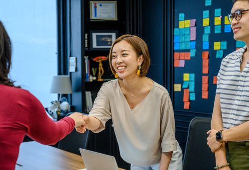 Free Three colleagues in a meeting room, with a woman smiling and shaking hands. Stock Photo