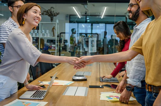 A diverse team of smiling professionals shaking hands during a productive meeting in a modern office.