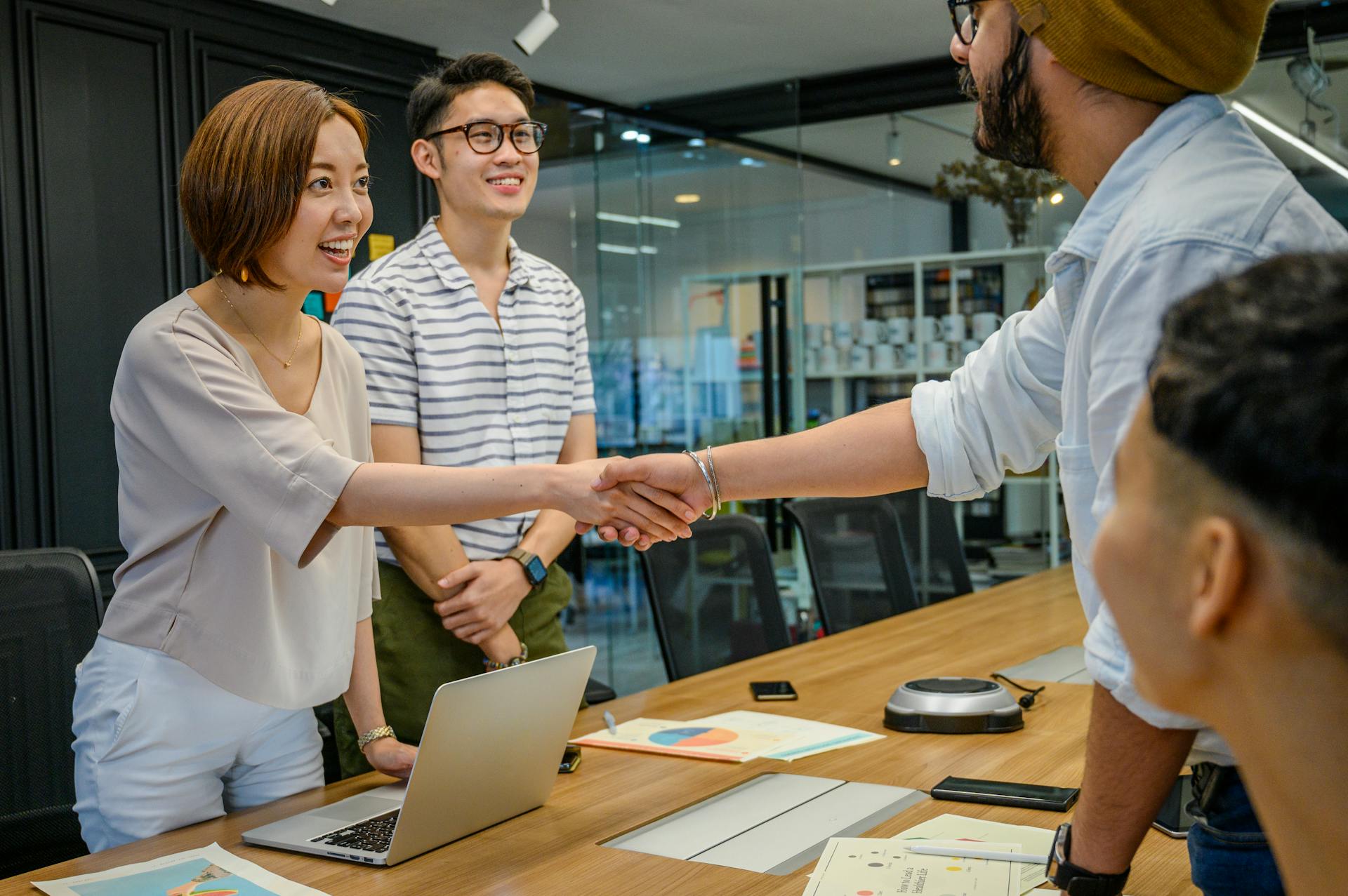 A diverse group having a productive business meeting with handshakes and smiles in a modern office.