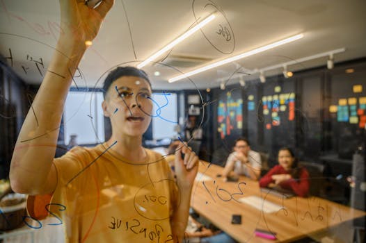 Team collaboratively brainstorming on transparent board in a modern office setting.