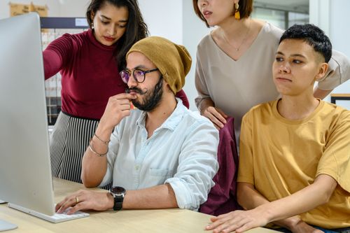 Free Diverse colleagues collaborating at a computer in a modern office setting. Stock Photo