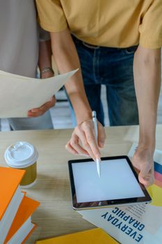 Two colleagues collaborate using a tablet in a modern office, focusing on teamwork and digital tools.