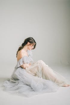 在极简主义的工作室环境中，一位美丽的女人穿着飘逸的连衣裙，优雅地摆着姿势