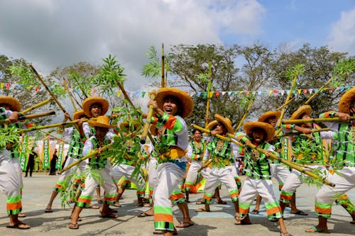Ethnic people wearing authentic traditional costumes and straw hats standing together with bamboo sticks in hands and screaming