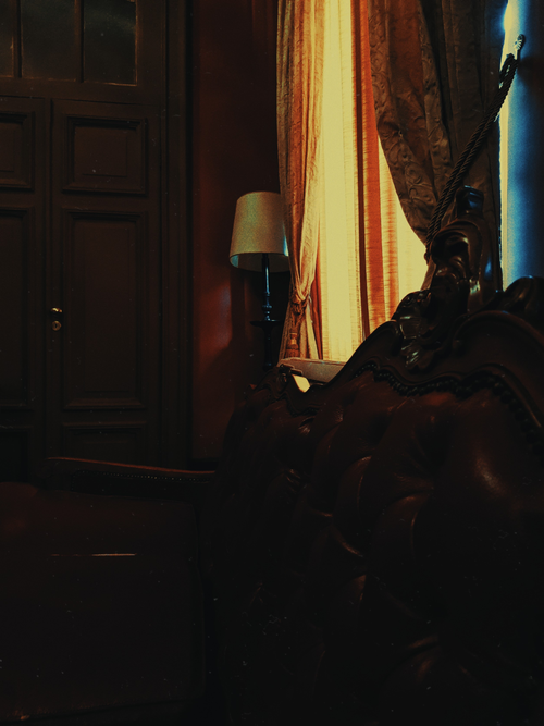 Free A moody vintage interior featuring an antique armchair, ornate curtains, and warm lighting. Stock Photo